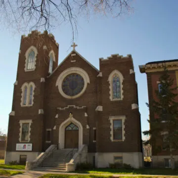 Front of City Church, a brown bricked building with asymmetric towers on the left and right side of the entrance.