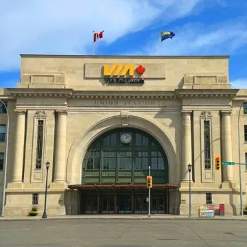 Front of Union Station, which has a large arch with windows and doors. On top of the are a sign says VIA.