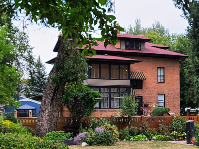 Rear of 3-storey brick exterior house with 1st floor and 2nd floor closed-in verandahs and dormer on roof