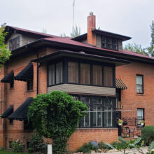 Image 1: Rear of 3-storey brick exterior house with 1st floor and 2nd floor closed-in verandahs and dormer on roof