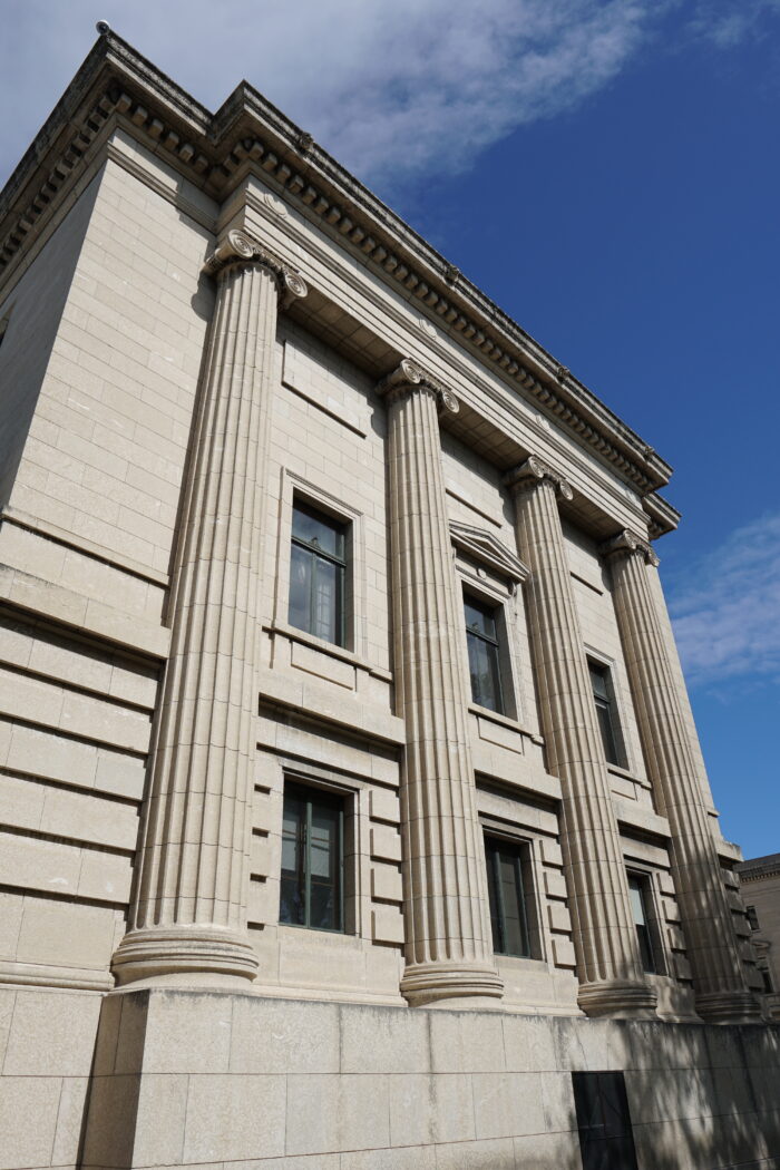 Side of the Legislative building where four columns protrude from the wall, with two rows of windows between the columns.