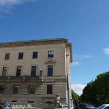 Image 1: One of the side facades of the Legislative building with cars in the parking lot