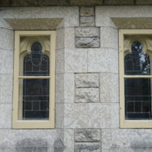 Image 11: Details on rectangular glass paned windows upon the stone facade of the church