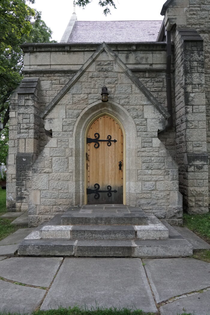 An entrance to Winnipeg’s St. John’s Cathedral. A light fixture hangs above the wooden door.