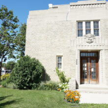 Image 3: Front facade of the Women's Tribute Memorial Lodge featuring front steps leading up the the wooden front doors