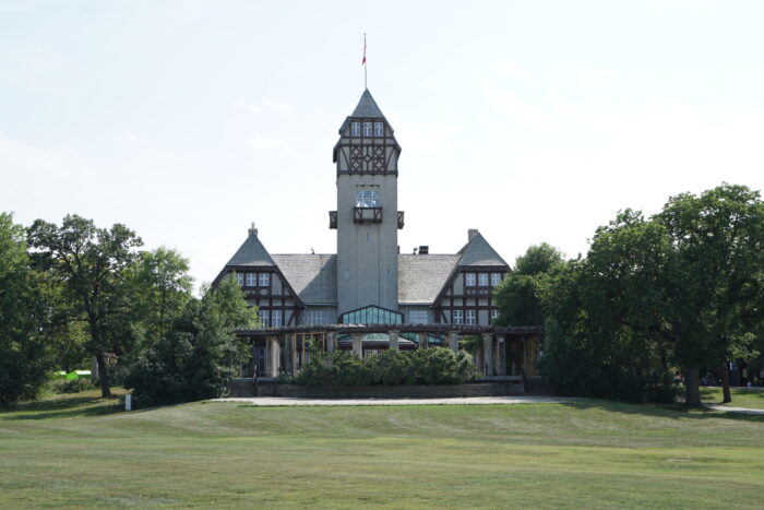 The back facade of the Assiniboine Park Pavilion. A Canadian flag flies atop the tower.