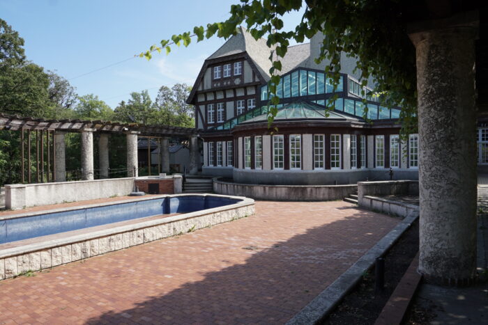 The back facade of the Assiniboine Park Pavilion with an empty pond in front of it.