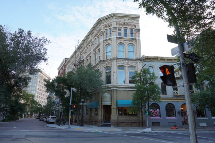 The Telegram Building with sidewalk trees partially obscuring the facade. Vehicles are parked on the street.