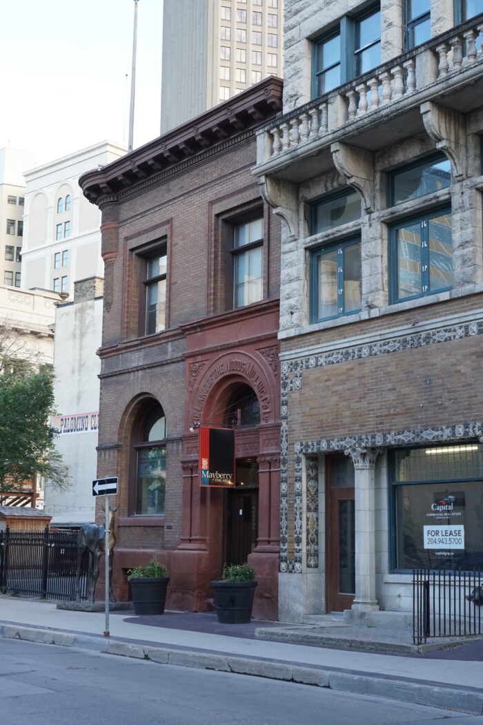 The Lake of the Woods Building with a sign reading “Mayberry FINE ART” hanging above the main entrance.