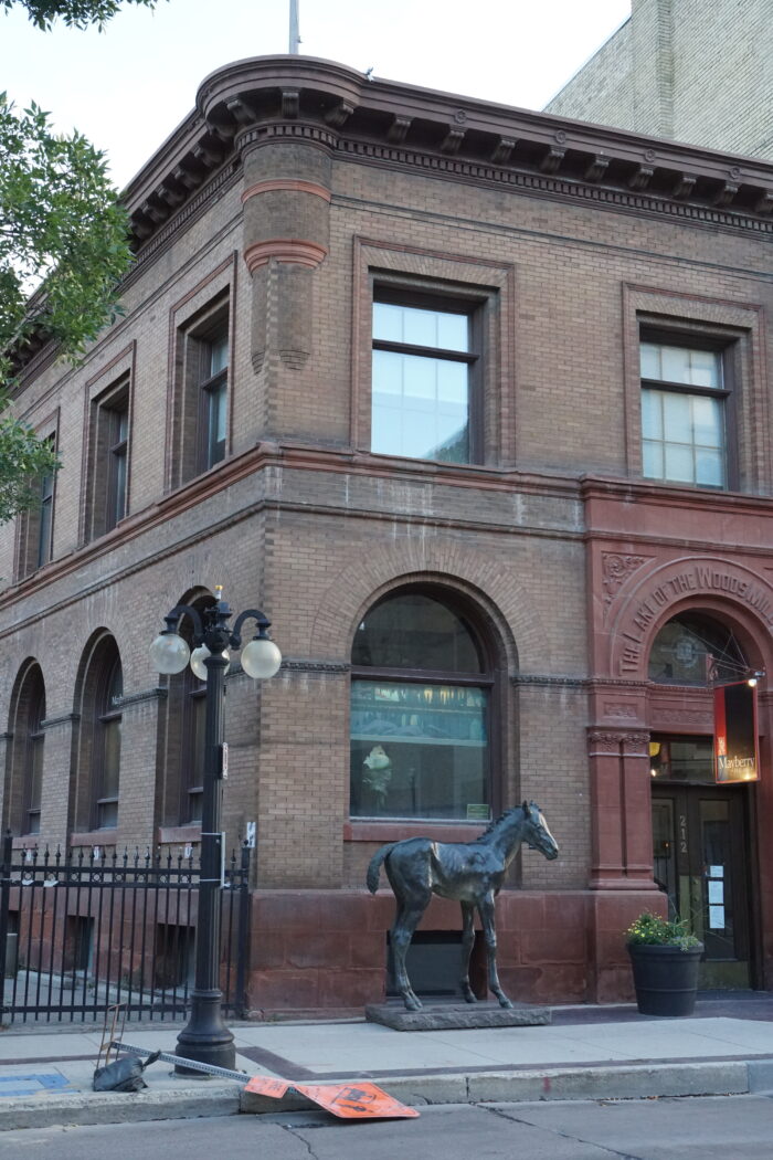 The Lake of the Woods Building with a streetlight, horse sculpture and planter in front.