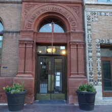 Image 3: Architectural details around the front doors featuring an arched window above surrounded in the red coloured material