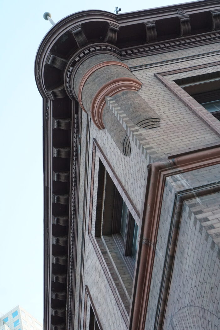 Looking up the facade of the building featuring 2 glass paned windows and details of the cornice