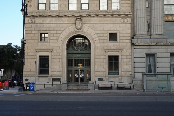 The front entrance of Winnipeg’s Bank of Hamilton with benches on the sidewalk against the building.