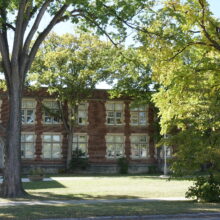 Image 8: Front facade of school partially obscured by trees