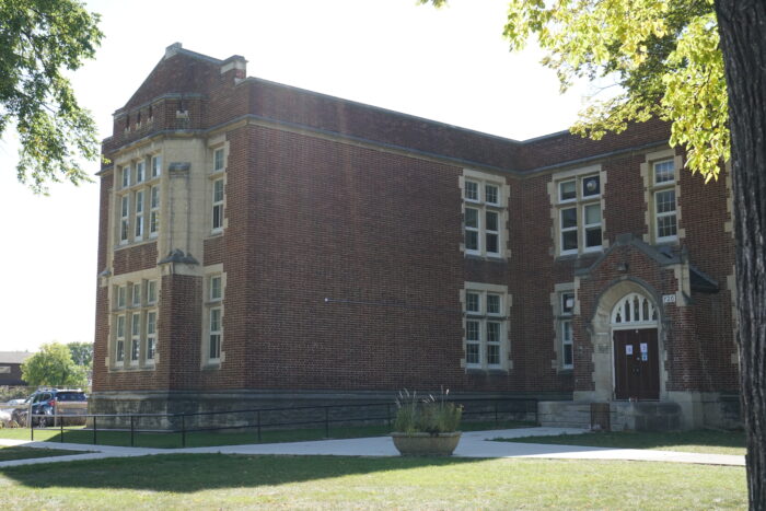 An entrance to Daniel McIntyre School. A planter sits on the sidewalk.