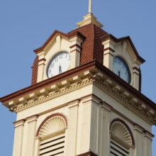 Image 2: Clock tower of the St. Boniface City Hall featuring details on the cornice and a clock on each side facing all directions