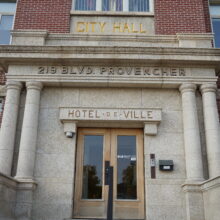 Image 6: Markings above the front door that reads "Hotel de Ville", "219 BLVD Provencher, "City Hall"