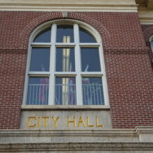 Image 7: Details of the central window on the front facade of the building that sits above the text that reads "City Hall"