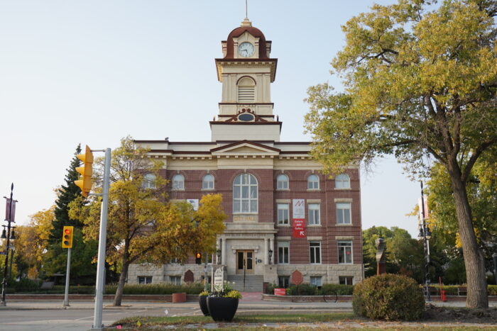 St. Boniface City Hall as seen from across the street. Stoplights and landscaping are in the foreground.