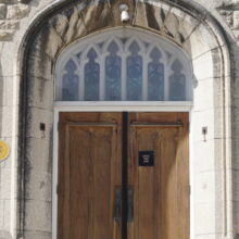 Image 9: Wooden doors leading into the building featuring glass-paned details above