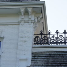 Image 11: White trimming and other decorative architectural details not he white exterior walls of Government House with the parapets on the roof in view