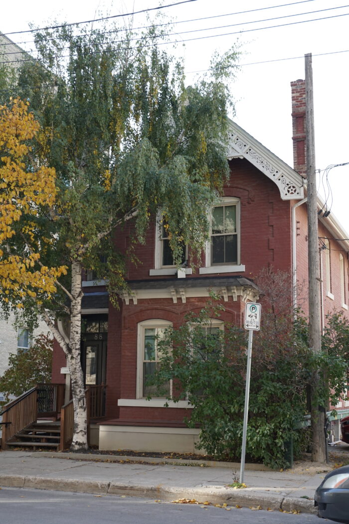 Kelly House with trees and bushes growing around it, obscuring the facades.