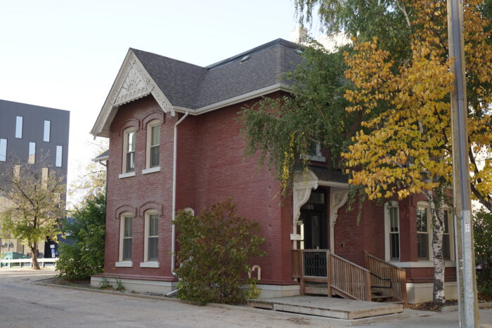 Kelly House with trees and bushes growing around it, obscuring the facades.