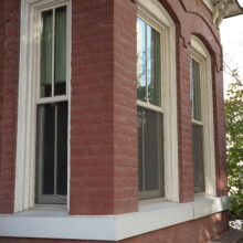 Image 3: A pair of main floor windows with arched stone trim