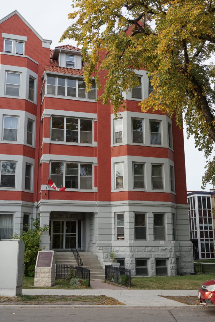 The front entrance of the Roslyn Court Apartments with a Canadian flag mounted above.