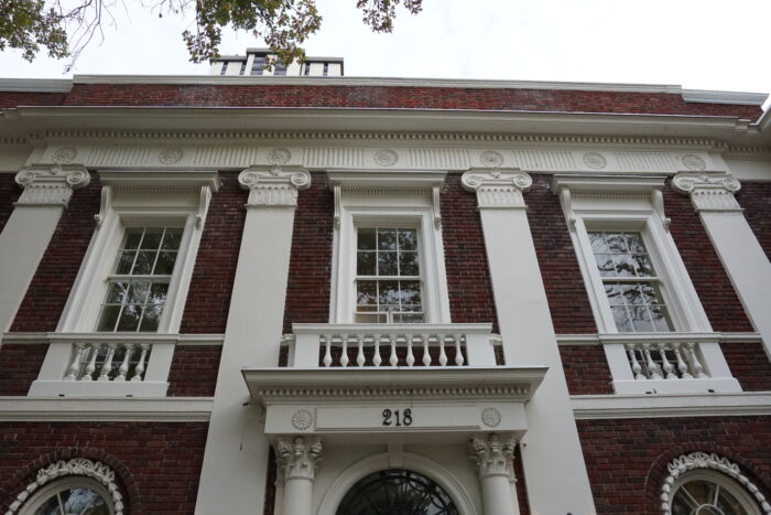 Looking up at the front facade of Moss House. The number “218” is mounted above the front entrance.