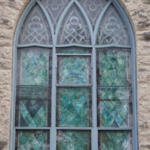 Image 6: Intricate details on a large glass paned windows on the facade of St. Luke's Church featuring coloured glass