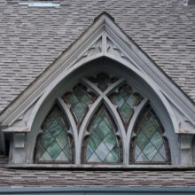 Image 7: Intricate details on coloured glass paned windows on one of the dormers on St. Luke's Church building