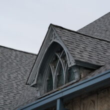 Image 8: Coloured glass paned windows on one of the dormers on St. Luke's Church building viewed from an angle