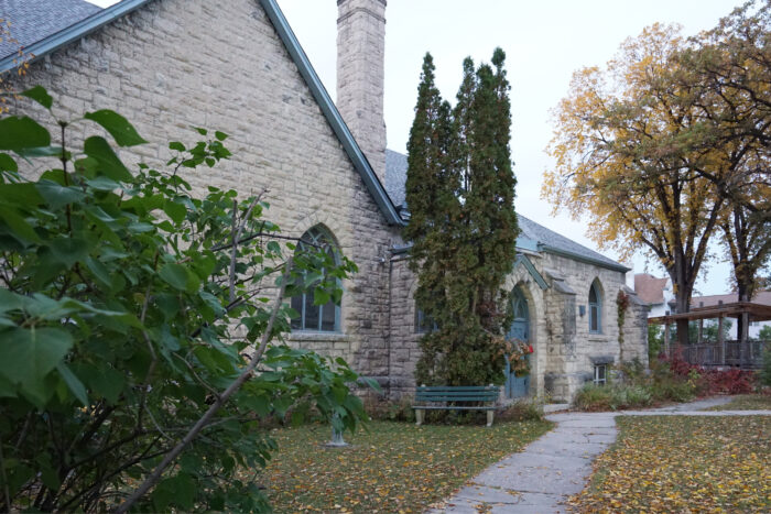 Stone pathway across lawn to pointed arched entrance on facade of stone church