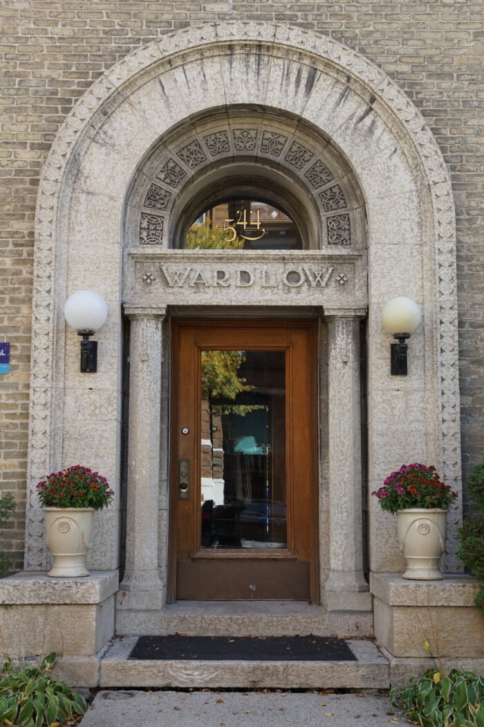 The front entrance of the Wardlaw Apartments with “544” on the transom window and “WARDLAW” carved below.