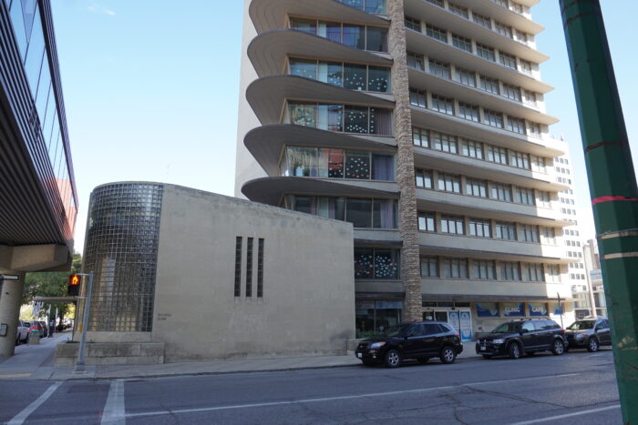 The Winnipeg Clinic building with three vehicles parked on the street in front.