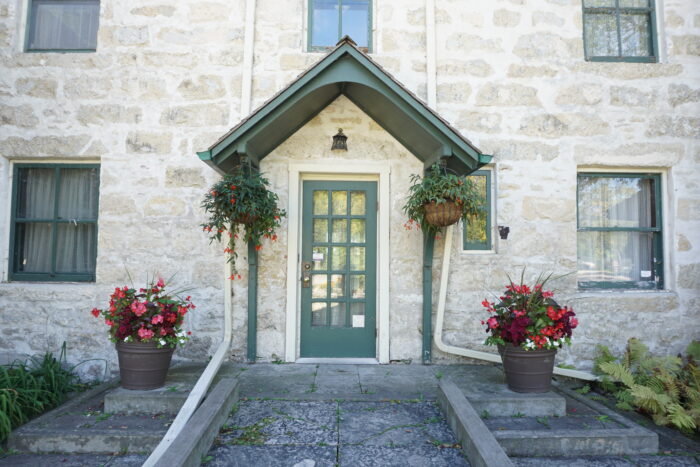 The green front door of Kennedy House, framed by hanging and potted plants.