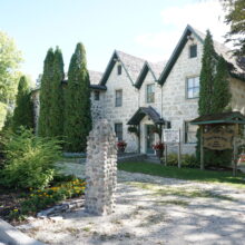 Image 4: Kennedy House with landscaping obscuring part of the facade. A sign reads “Captain Kennedy House.”