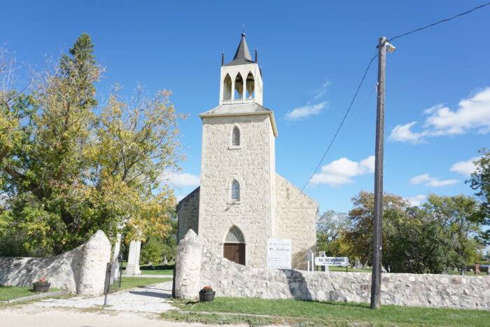 St. Andrews Church behind a stone wall. A sign in the yard reads “NO TRESPASSING AFTER DUSK.”