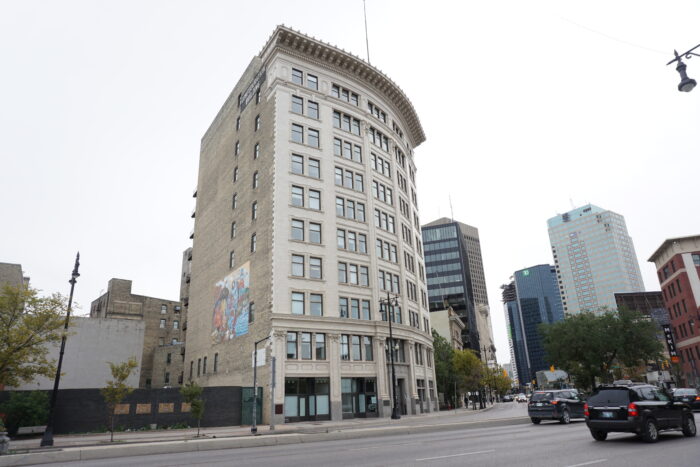 The Confederation Life Building as seen from across the street. A mural is visible on the side of the building.