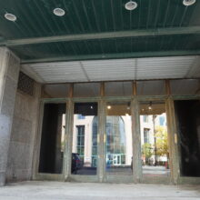 Image 12: Details on one of the entrances into the Hudson's Bay Company building featuring brarss-coloured doors and glass panes