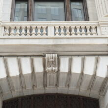 Image 1: Details on the stone arch above an entrance, looking up at a Juliette balcony