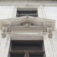 Image 3: Looking up a decorative pediment above an entrance with intricate detailing in stone