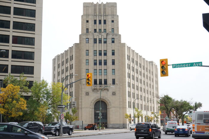 Le bâtiment fédéral vu de l'autre côté de la rue. Feux de signalisation avec un panneau indiquant Pioneer Ave au premier plan.  