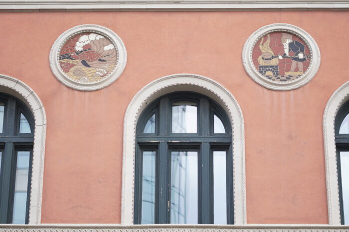 A window on the third storey of the Birks Building (Former YMCA) framed by two medallions.