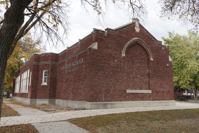 Wolseley School with “WOLSELEY SCHOOL” and “511 CLIFTON STREET” posted on the facade. Trees grow behind,