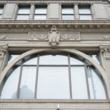 Image 2: Arched glass paned windows featuring decorative architectural details on the exterior walls