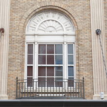 Image 2: Glass paned windows on the facade of the Metropolitan Theatre featuring decorative arched accents and iron juliette balcony