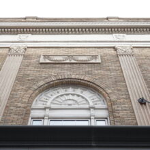 Image 3: Looking up the facade of the Metropolitan Theatre featuring decorative architectural details and a view of the cornice