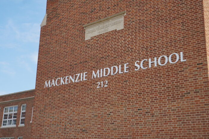 Looking up brick end wall of extension with school name on it.